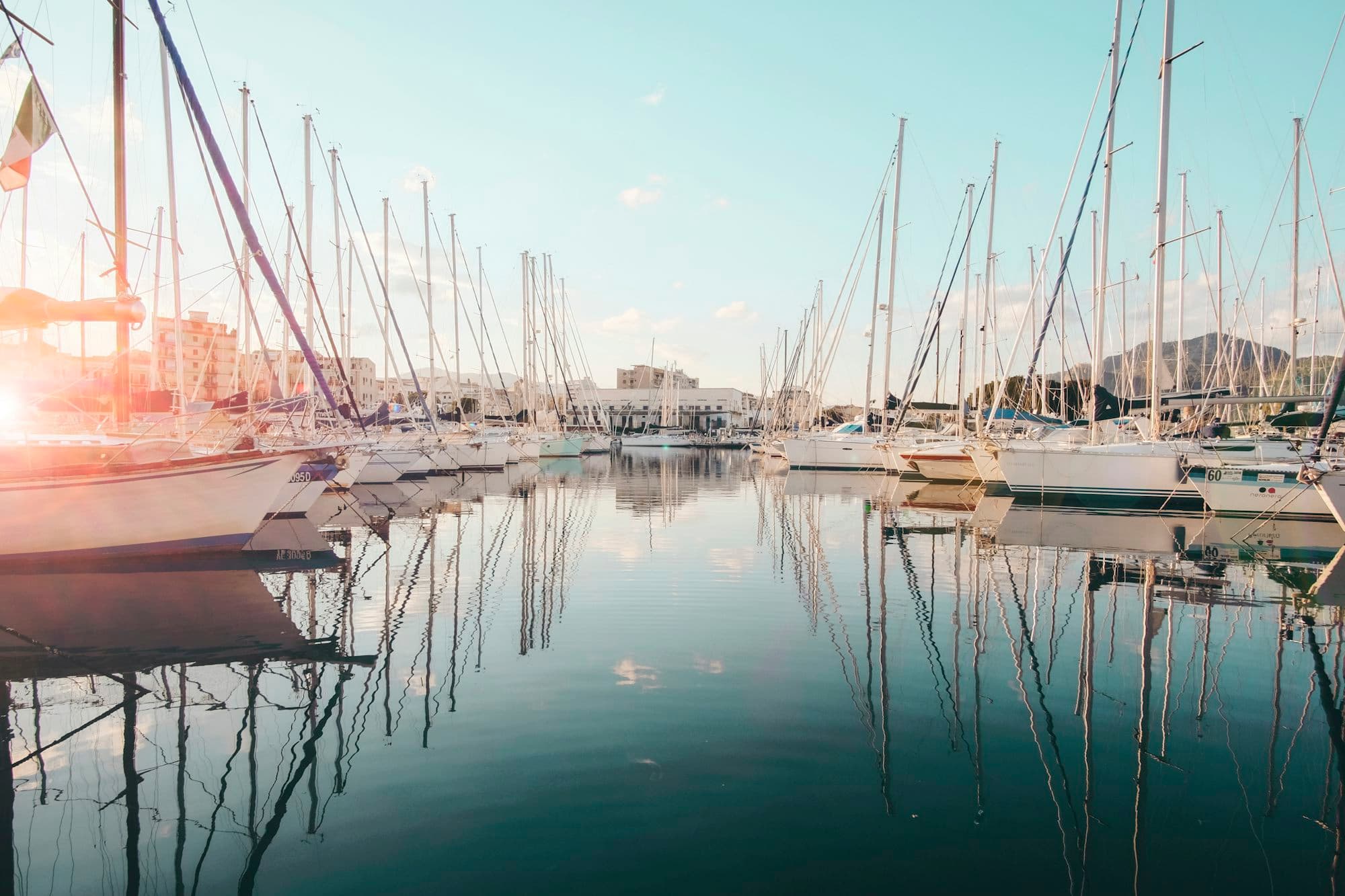 A row of cruising sailboats in their marina at dusk