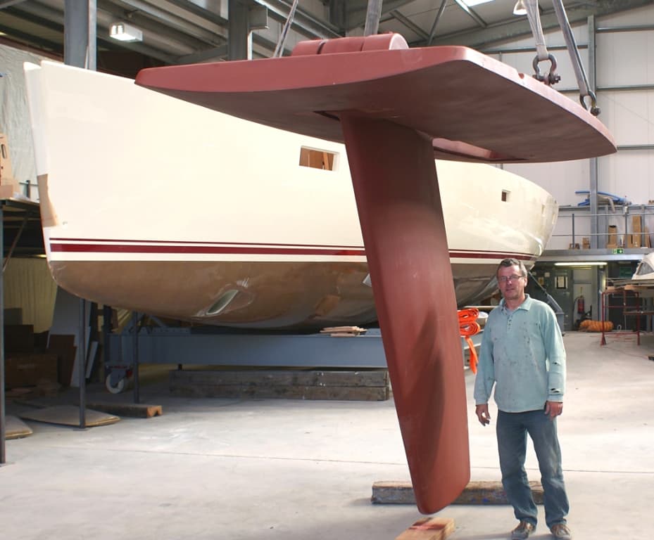 A Southerly variable-draft keel out of the hull at the factory, a person beside it for scale