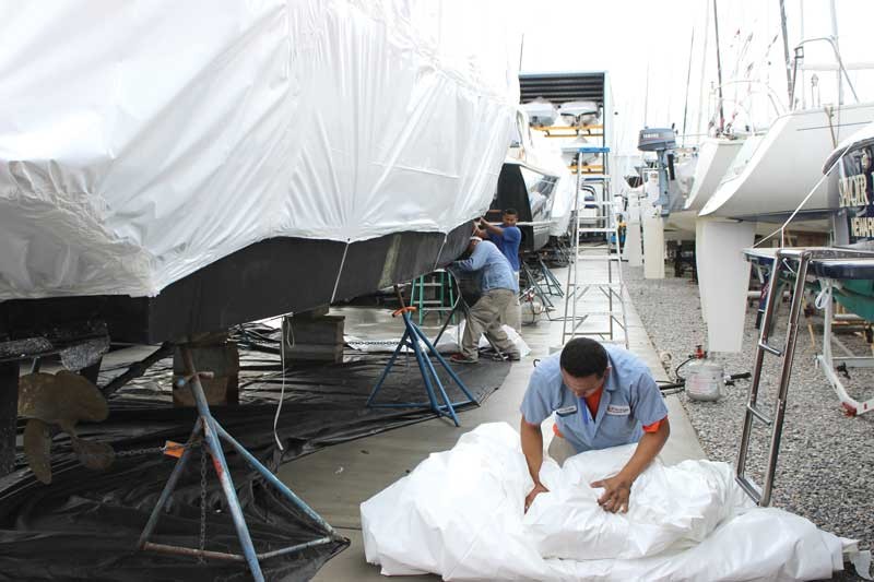 Marine technicians removing boat shrink wrap.