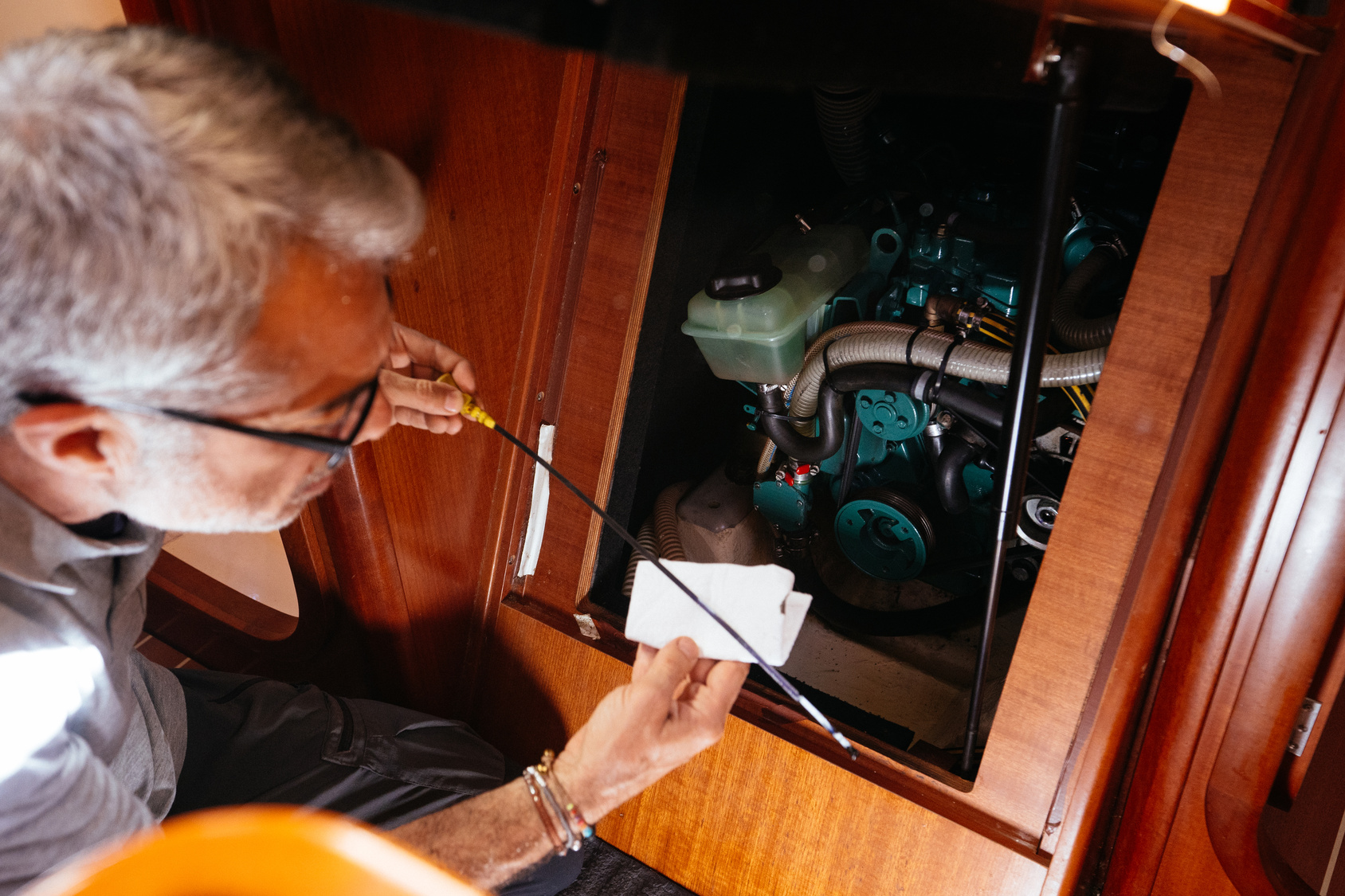 Senior mechanic checking oil level of engine on yacht with dipstick From above of male senior technician checking oil level of engine with dipstick while working on yacht